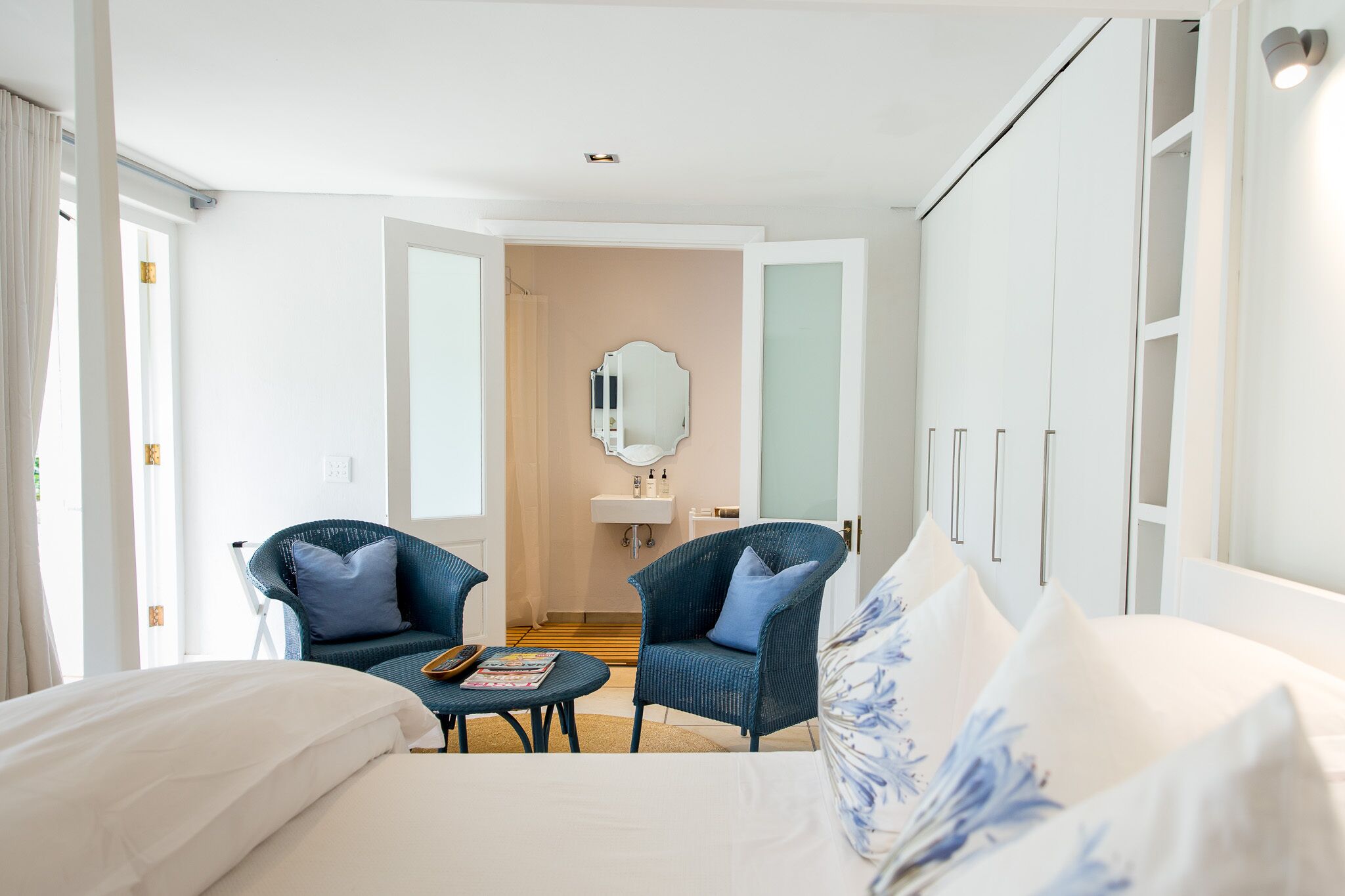 Una habitación de hotel con una cama, dos sillones, una mesita, un espejo y un armario.