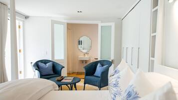 Una habitación de hotel con una cama, dos sillones, una mesita, un espejo y un armario.