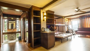 A hotel room with a wooden vanity, a bed, a seating area, and a staircase leading to another level. - West 35 Eco Mountain Resort (Balamban)