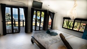 Une chambre avec un lit, une vue sur la mer et un balcon équipé de chaises.