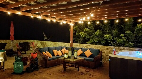 Un área de estar al aire libre con un sofá, una mesa y jarrones decorativos.