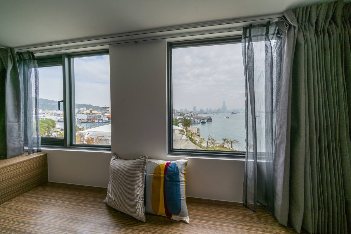 Ein Zimmer mit einem großen Fenster, einer Bank und zwei Kissen.