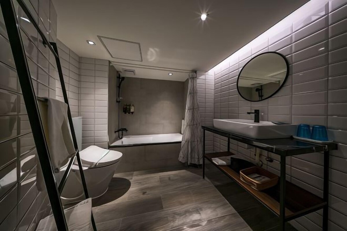 A modern bathroom with a bathtub, toilet, and vanity with a mirror.
