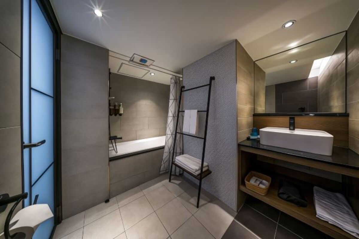 Une salle de bain moderne avec un grand miroir, un lavabo et un espace douche.