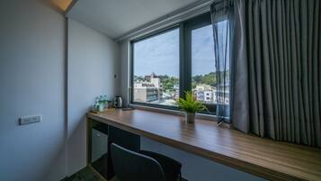 Edredón, escritorio, cortinas blackout y tabla de planchar con plancha