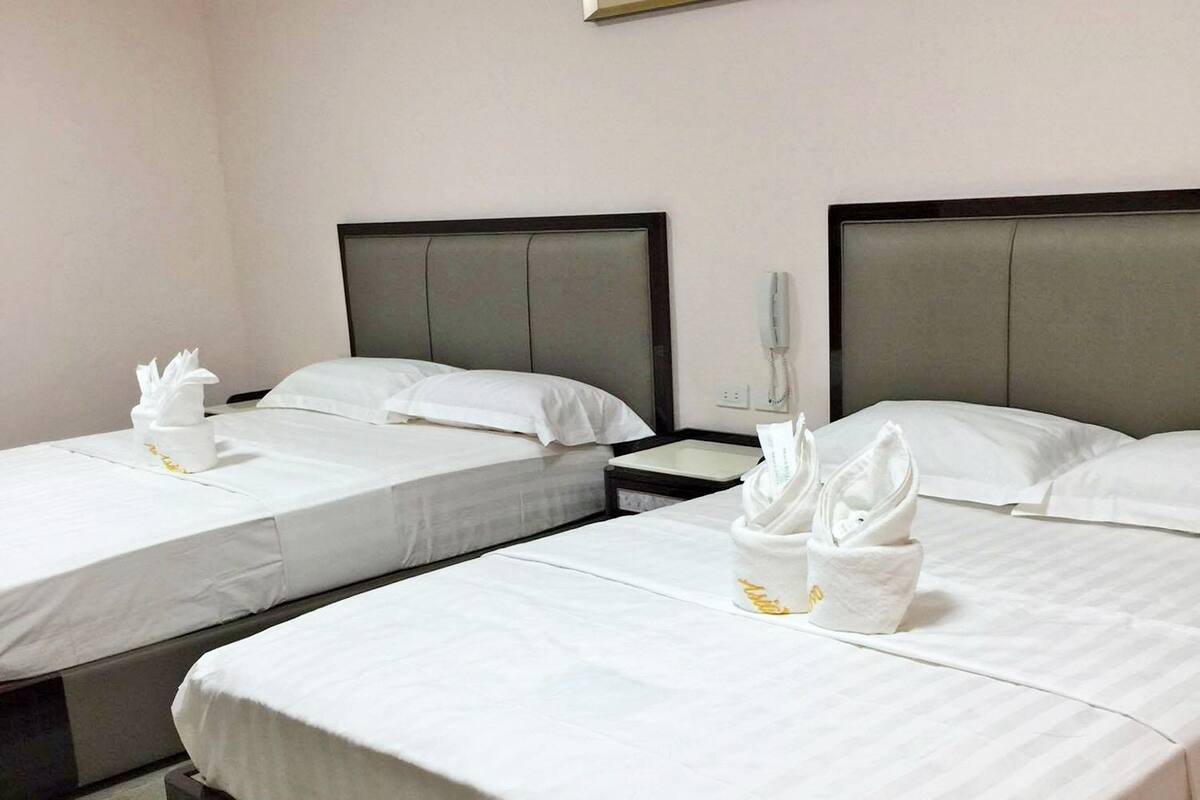 Hotellihuoneessa on kaksi sänkyä, joissa on valkoiset lakanat ja pyyhkeet. Sänkyjen yläpuolella on kehystetty taideteos ja yöpöydällä puhelin.