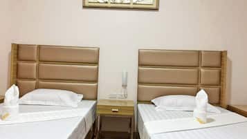 Hotellihuoneessa on kaksi sänkyä, joissa kummassakin on pääty ja valkoiset vuodevaatteet. Sänkyjen välissä on yöpöytä, jossa on lamppu ja puhelin. Sänkyjen yläpuolella seinällä on kehystetty taideteos.