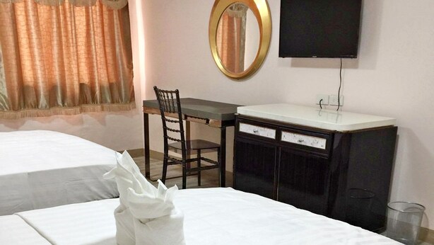 A hotel room with two beds, a desk, a chair, a television, and a mirror. - Meaco Royal Hotel - Lipa (Lipa)