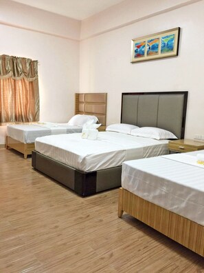 A hotel room with three single beds, a wooden floor, and a painting on the wall. - Meaco Royal Hotel - Lipa (Lipa)
