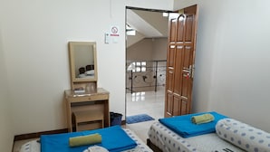 Una habitación con dos camas, un escritorio, un espejo y una puerta que da a un balcón.