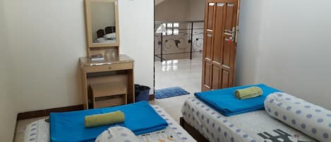 A room with two beds, a desk, a mirror, and a door leading to a balcony.