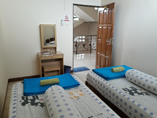 Quarto com duas camas, uma escrivaninha, um espelho e uma porta que dá para uma varanda.