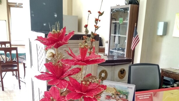 Un mostrador de recepción con un gran arreglo floral artificial.