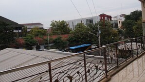Vista desde un balcón con barandilla de metal, que da a una calle con edificios y árboles.