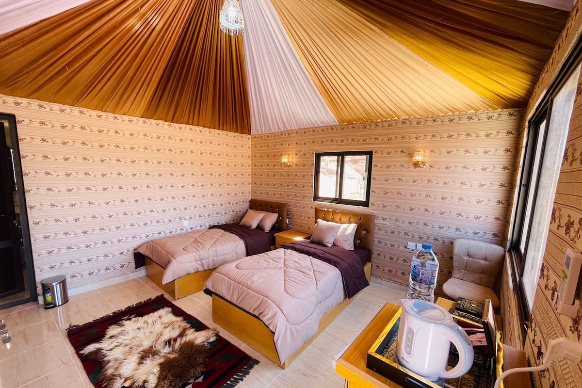 Una habitación acogedora con dos camas, techo de madera y un pequeño escritorio con un hervidor.