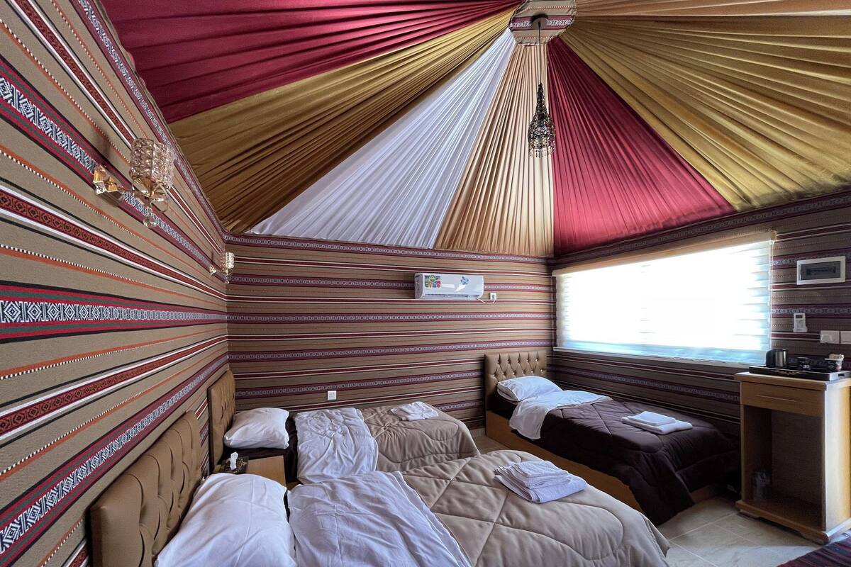 Una habitación con dos camas, un escritorio y una ventana.
