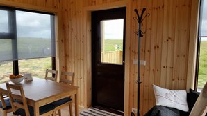 Ein Holzinterieur mit einem Esstisch, Stühlen, einer Bank und einer zur Außenseite führenden Tür.