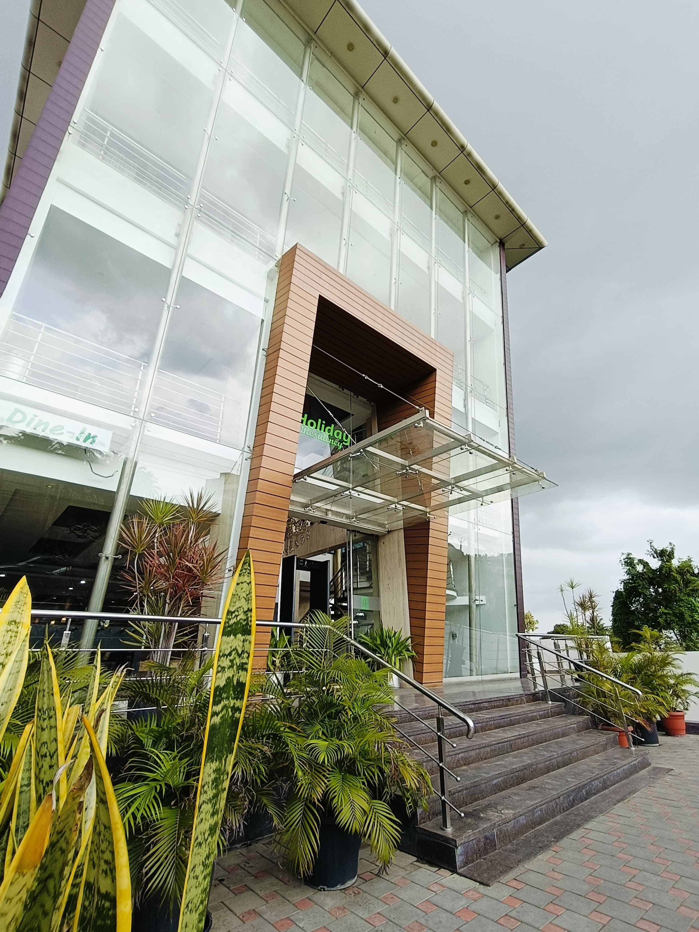 A modern building with a glass entrance, a brick base, and a staircase leading to the entrance.