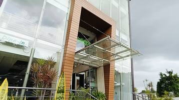 A modern building with a glass entrance, a brick base, and a staircase leading to the entrance.