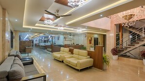 Vestíbulo de hotel con recepción, sofás, una escalera y un ventilador de techo.