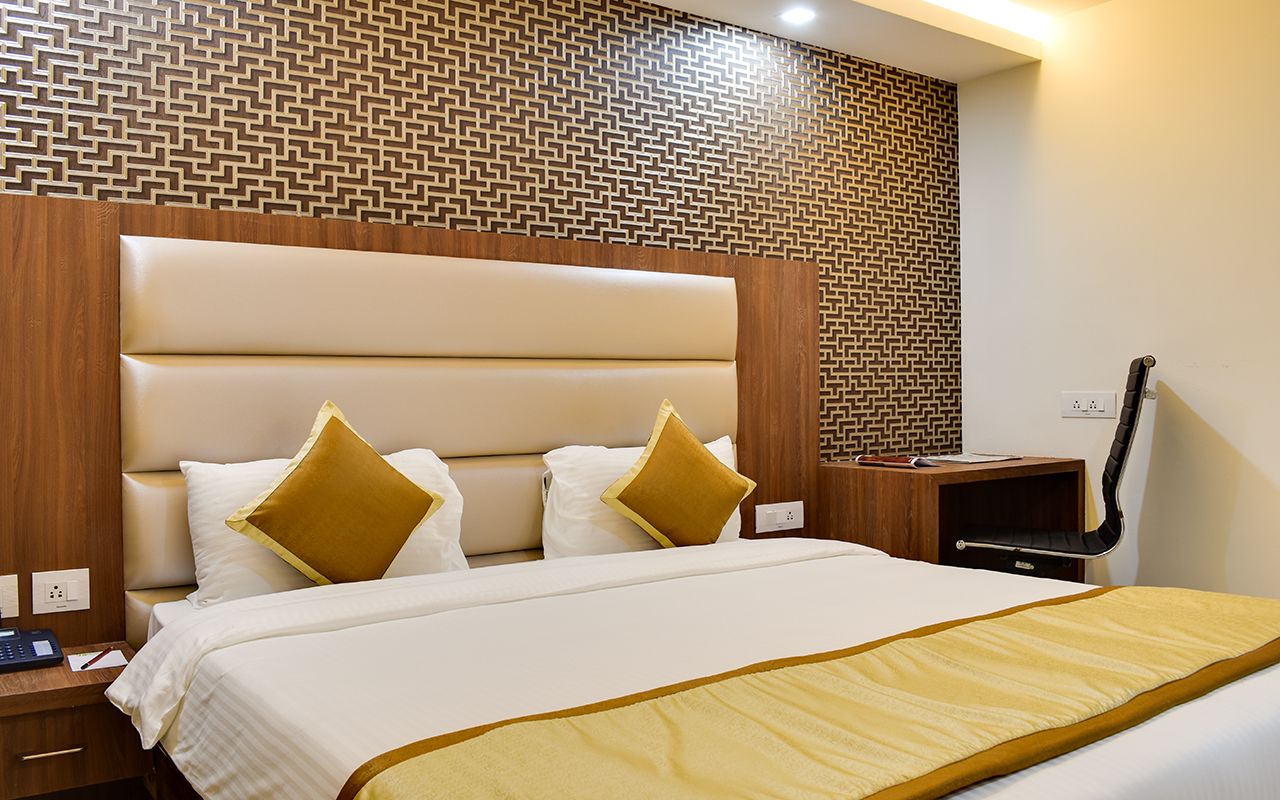 Habitación de hotel con una cama grande, cabecero de madera y pared con diseño.