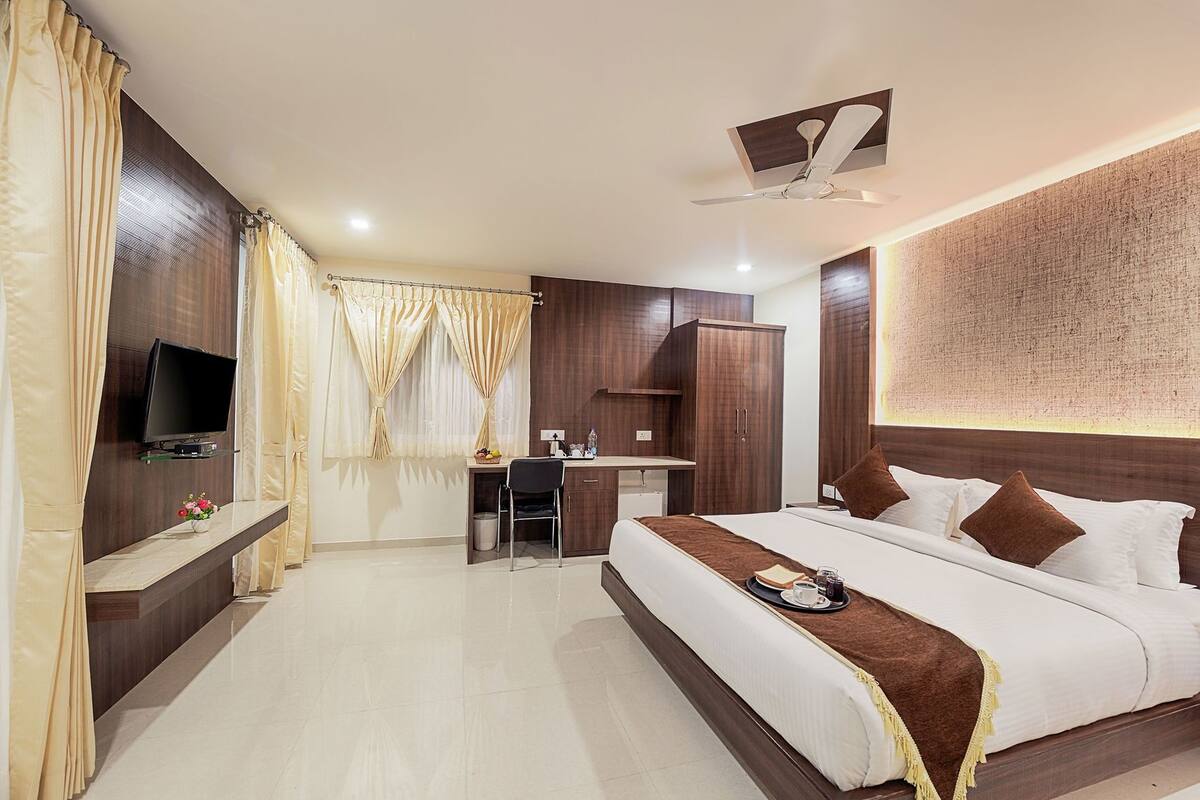 A hotel room with a bed, desk, TV, and wardrobe.