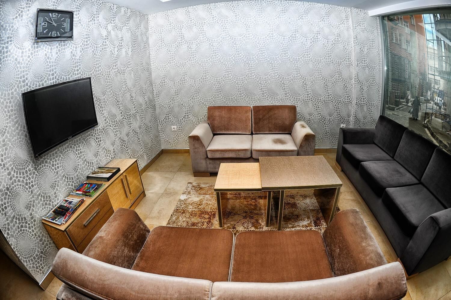 A living room with a sofa set, a coffee table, and a flat-screen TV mounted on the wall.