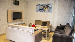 Un salon moderne avec un ensemble de canapés, une table basse et un téléviseur à écran plat fixé au mur.