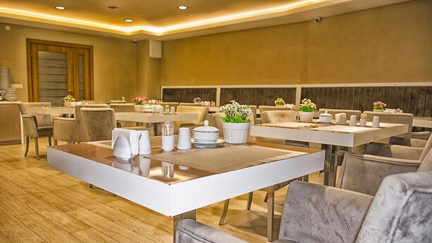 Un espace repas moderne avec des tables blanches et des chaises grises recouvertes de tissu.
