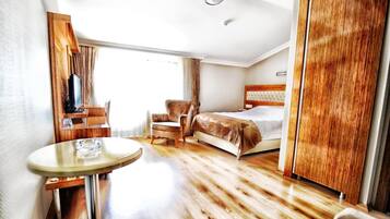 Habitación de hotel con cama, una silla, una mesa y un armario.