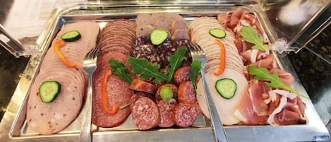 Un bufé con diferentes carnes en rodajas y guarniciones.