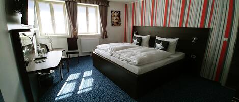 Hotellihuone, jossa on sänky, työpöytä, tuoli ja patteri.
