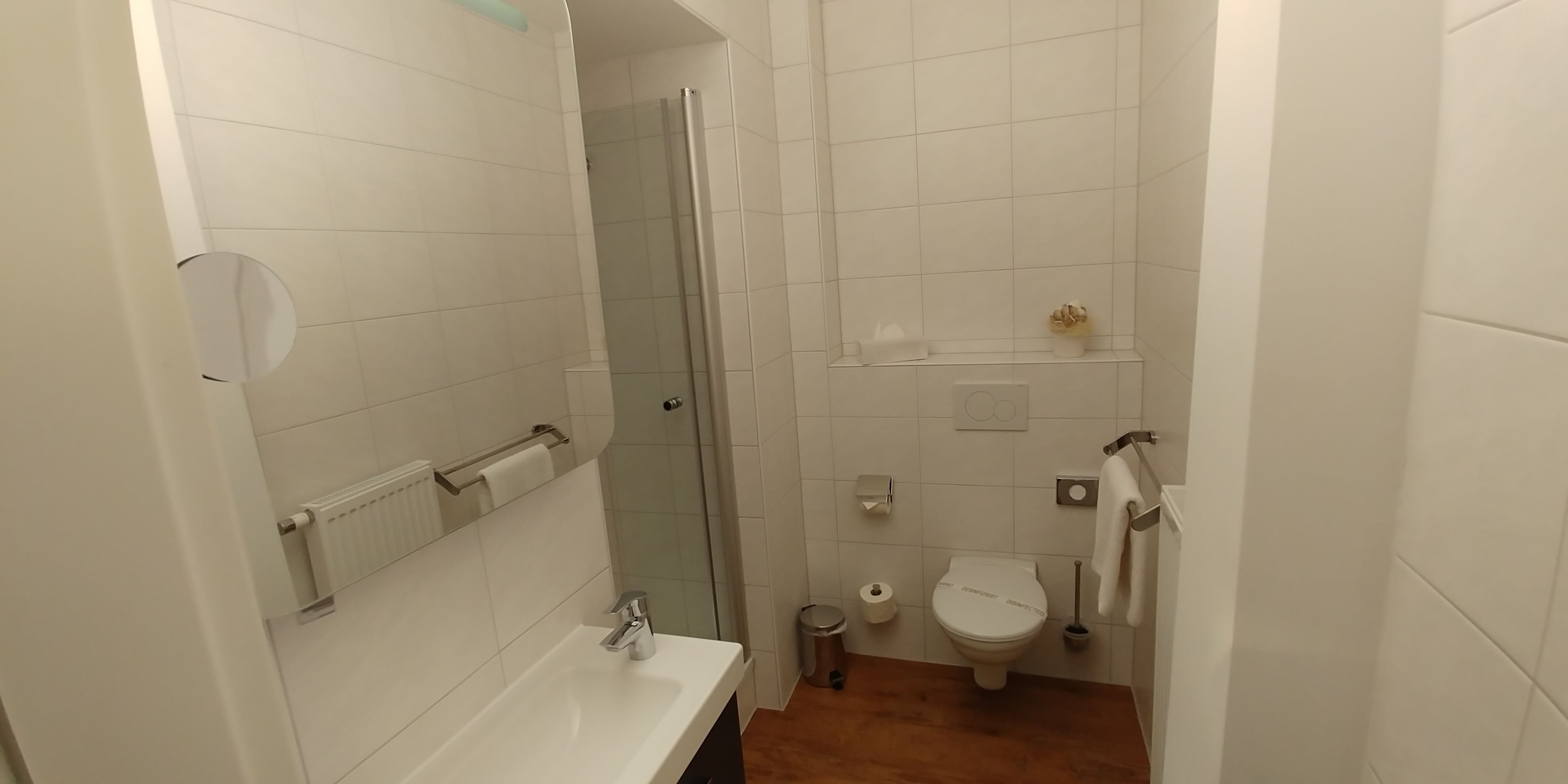 A bathroom with a white sink, toilet, and shower.