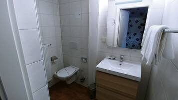 Un baño pequeño y limpio con inodoro, lavamanos y espejo.