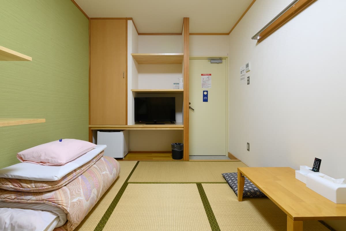 A compact room with a bed, a desk, a television, and a small refrigerator.