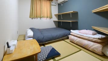 Una habitación pequeña y ordenada con una cama, una mesita de noche, una silla y una estantería.