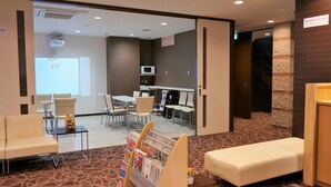 A hotel lobby with a reception desk, seating area, and a conference room with a projector. - Tabist Yuen no yado Fujimi (Fuji)
