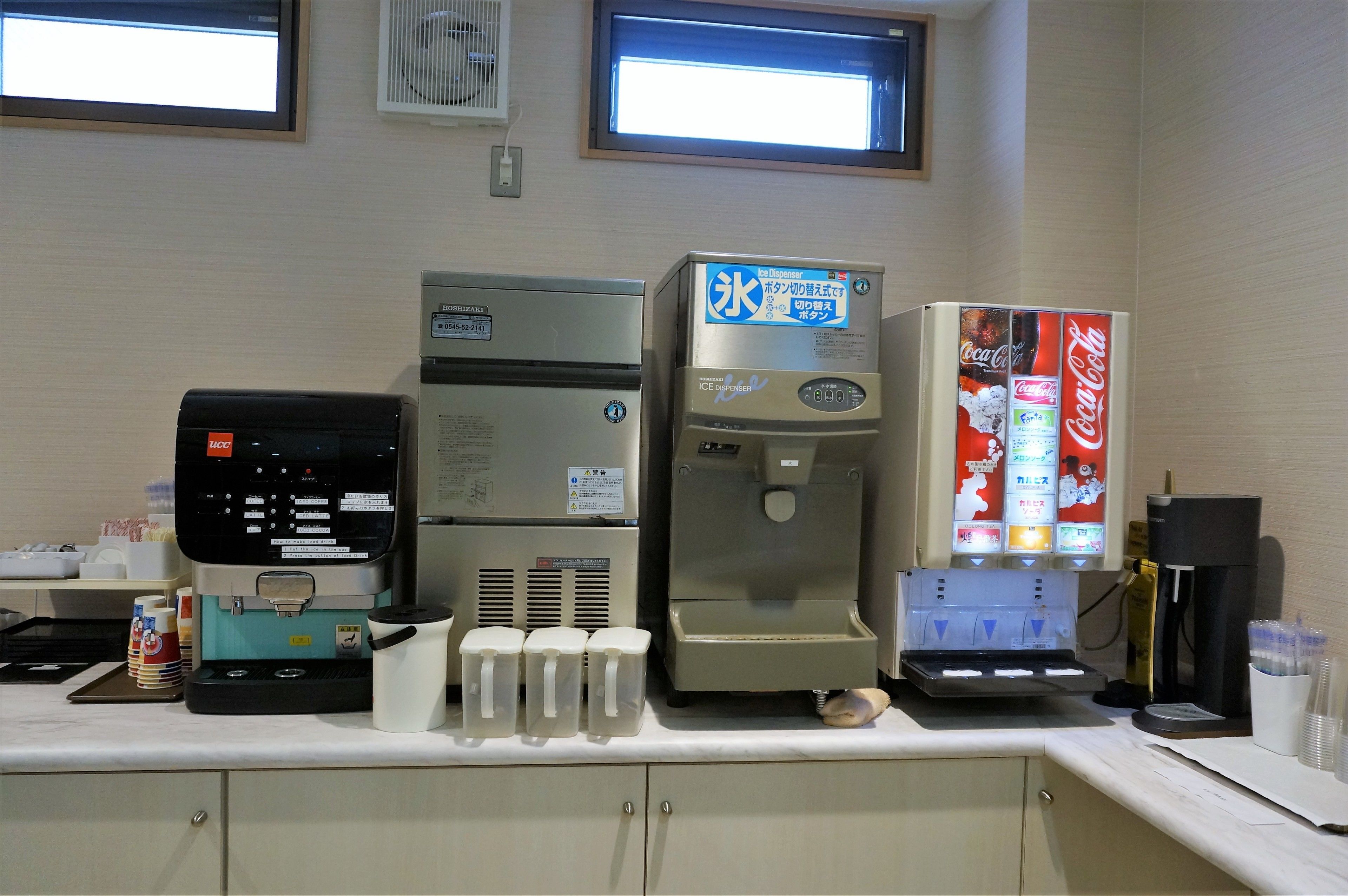 A coffee station with a coffee maker, an ice dispenser, and a Coca-Cola dispenser.