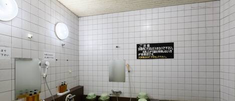 A public bath with multiple hot tubs, a green mat, and a sign with instructions.