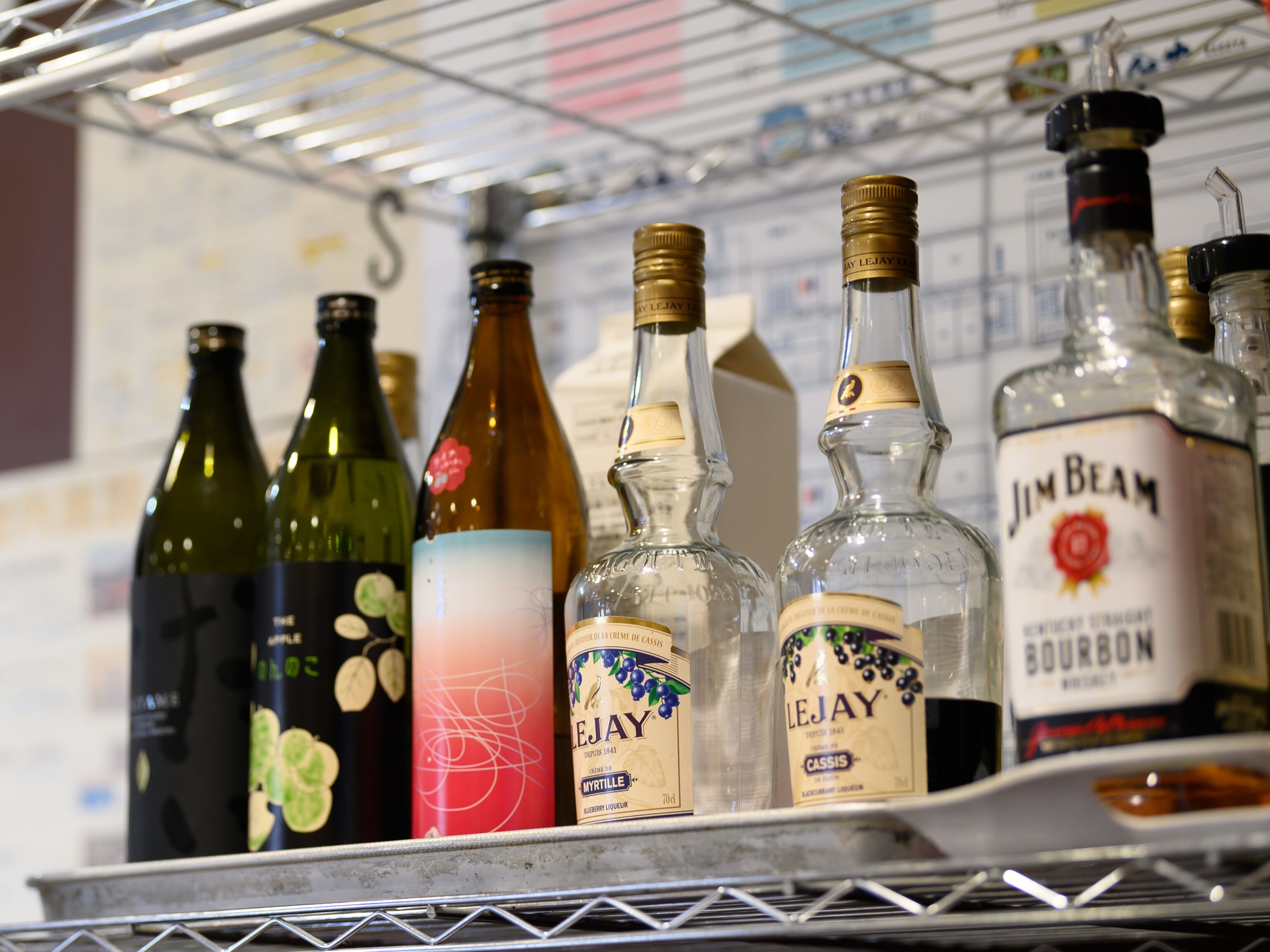 A shelf with various liquor bottles, including brands like Jim Beam and Le Jay.
