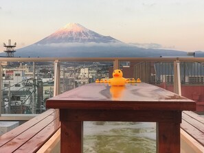 Ein Tisch mit Gummienten auf einem Balkon mit Blick auf eine Stadtlandschaft und ein Gebirge.