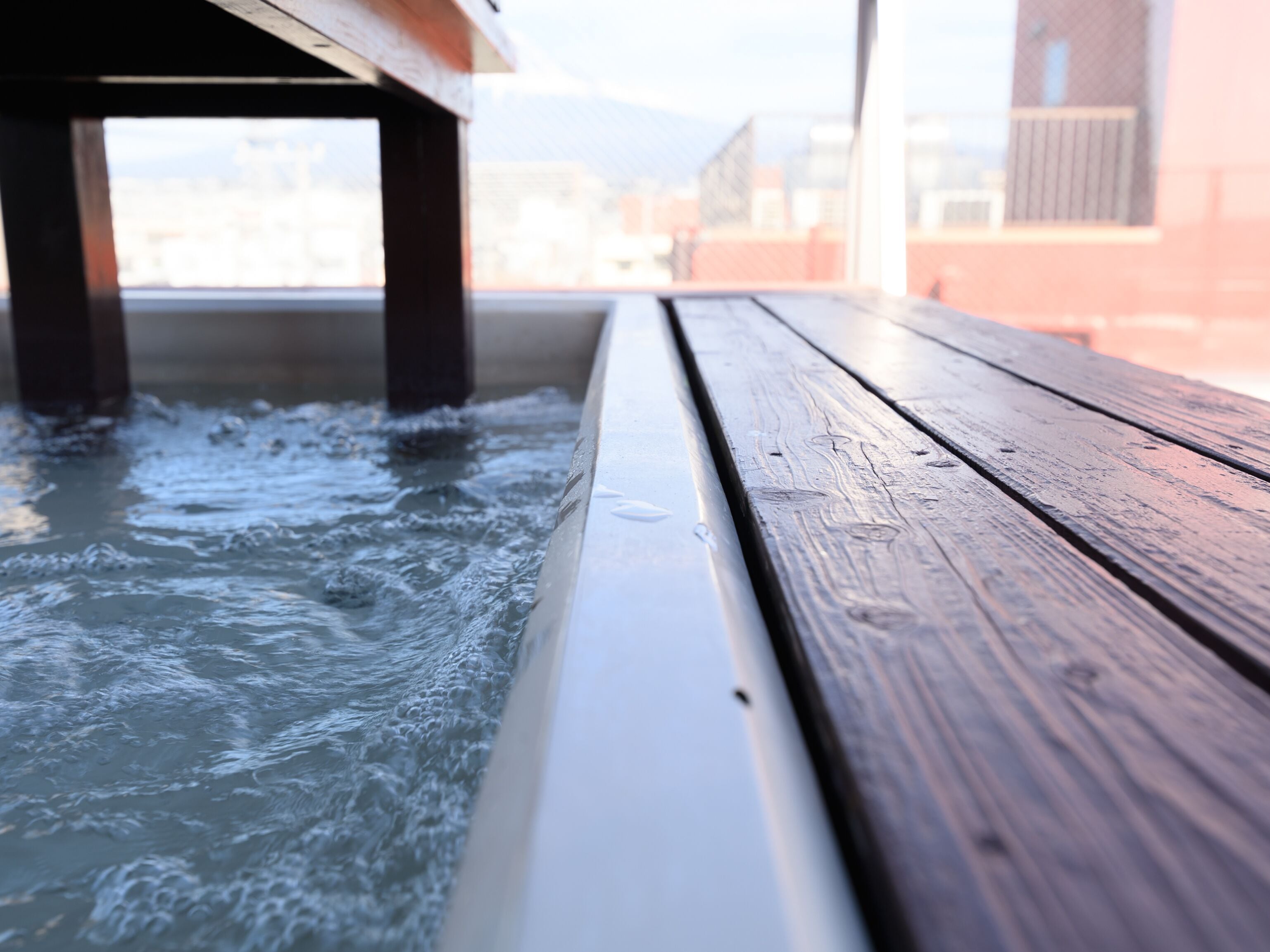 Un banco de madera con vista al agua que fluye bajo una estructura.
