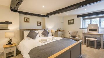 A bedroom with a large bed, bedside tables, a chair, a desk, and a window.