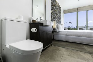 A modern bathroom with a toilet, dark wooden cabinet, and a large mirror.