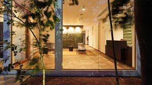 A modern interior with a central seating area, a staircase, and a glass wall reflecting the outside. - ME Colombo (Colombo)