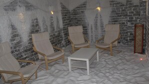 Una habitación con cuatro sillas color beige, una mesa blanca y una pared de ladrillo.