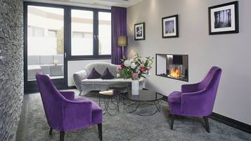 Una sala de estar moderna con un sofá, dos sillones morados, una mesa de centro y una chimenea.