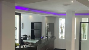 Un espace d’accueil moderne avec un comptoir d’accueil foncé, un téléviseur à écran plat et une cloison en verre.