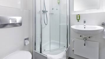 Une salle de bain moderne avec une douche à parois de verre, un lavabo blanc et des toilettes.
