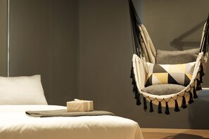 A modern bedroom with a bed, a hanging chair, and a small gift on the bed. - The Hammock Hotel Ben Thanh (Ho Chi Minh City)